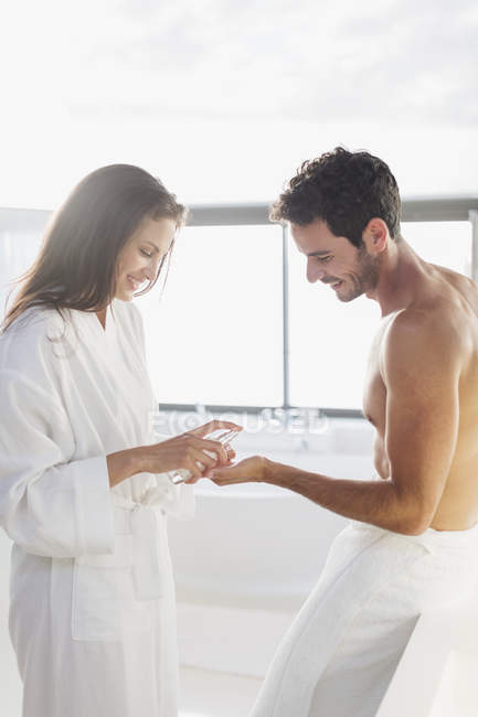 Woman dispensing moisturizer in man hand — Stock Photo