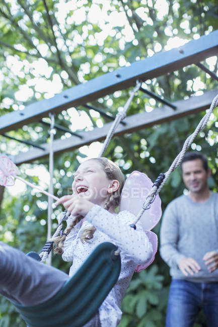 Père poussant fille sur swing à l'extérieur — Photo de stock