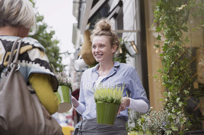 Fiorista che mostra le piante per shopper femminile in vetrina — Foto stock