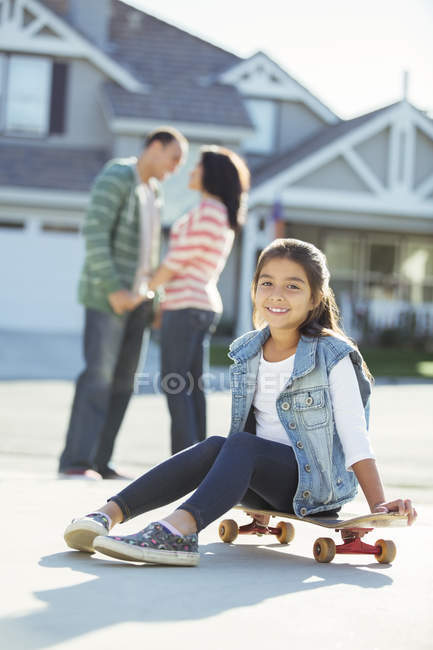 Portrait of smiling girl on skateboard in driveway — Stock Photo