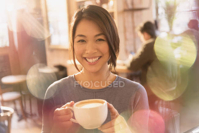 Портрет усміхненої жінки, що п'є капучино в кафе — стокове фото