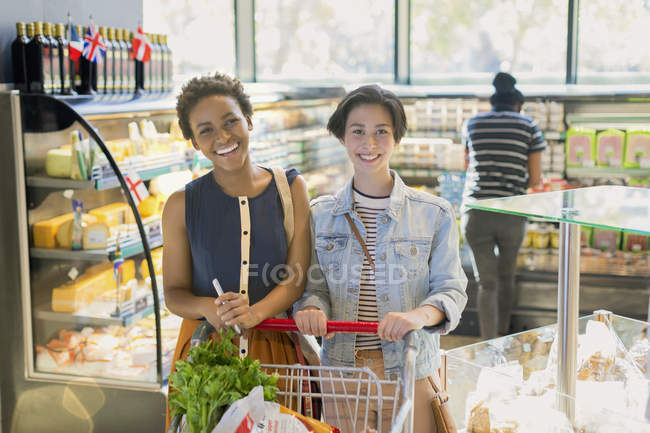 Портрет, улыбающаяся молодая лесбийская пара, продуктовый магазин на рынке — стоковое фото