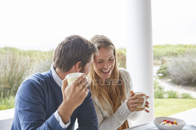Riendo pareja bebiendo café en el patio - foto de stock