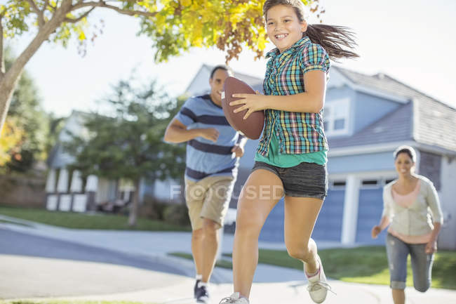 Famiglia giocare a calcio in strada soleggiata — Foto stock
