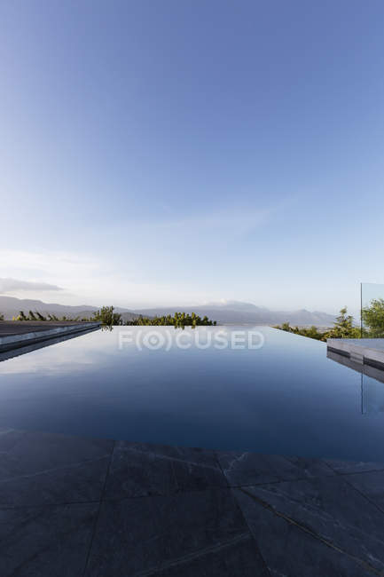 Tranquilo piscina de luxo infinito abaixo do céu azul — Fotografia de Stock