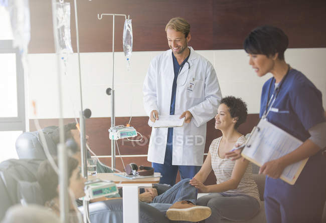 Médicos que asisten a pacientes que reciben perfusión intravenosa en el hospital - foto de stock