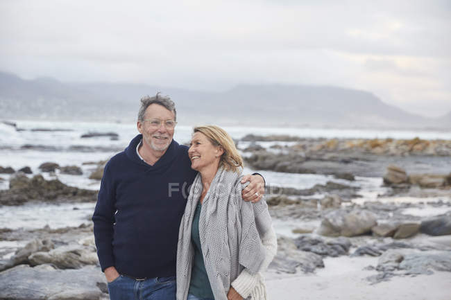 Sonriendo pareja mayor caminando en la playa de invierno - foto de stock