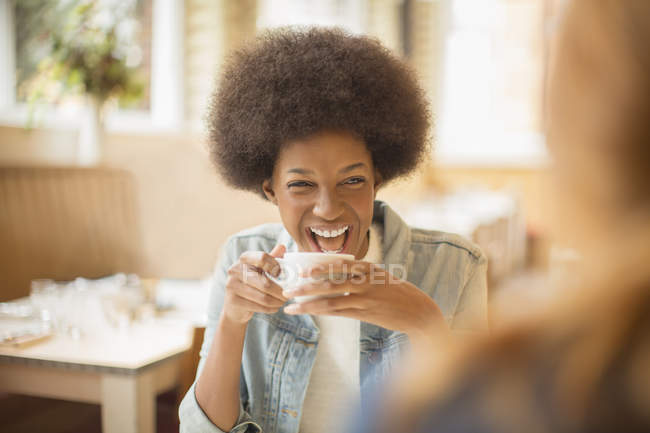 Happy young women drinking coffee in cafe — Stock Photo