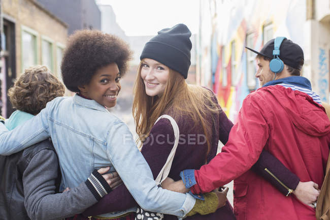Vista trasera de amigos caminando juntos en la calle de la ciudad - foto de stock
