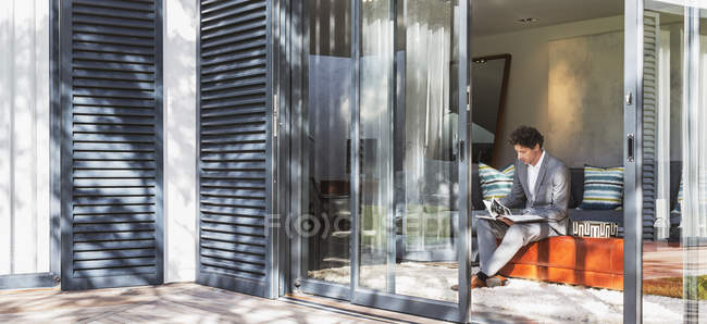 Geschäftsmann arbeitet im Wohnzimmer mit Blick auf sonnige Terrasse — Stockfoto