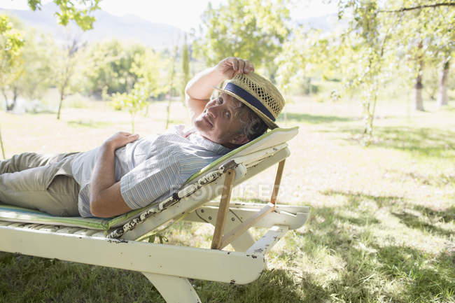 Літній чоловік розслабляється на кріслі на відкритому повітрі — стокове фото