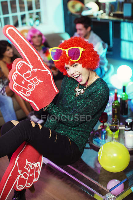 Woman wearing wig, oversized sunglasses and foam finger — Stock Photo