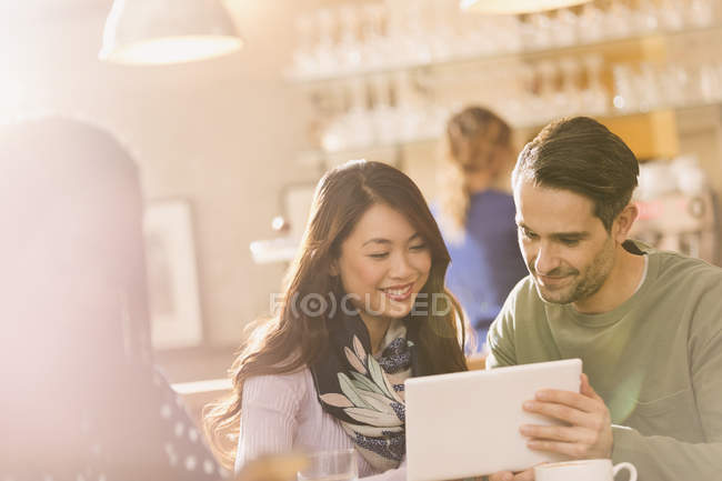 Happy adult friends using digital tablet in cafe — Stock Photo