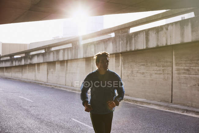 Male runner running into urban tunnel — Stock Photo