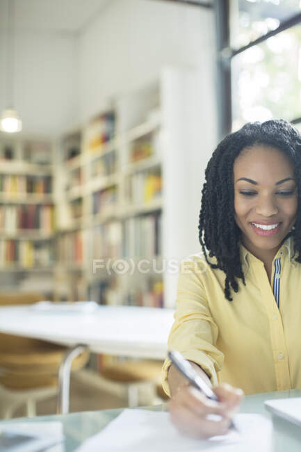 Smiling businesswoman writing on paperwork — Stock Photo
