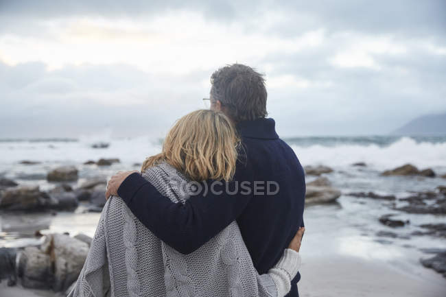 Heiteres Paar umarmt sich am Winterstrand — Stockfoto