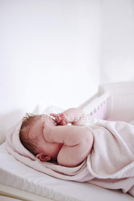 Baby rubbing her eyes on changing table — Stock Photo