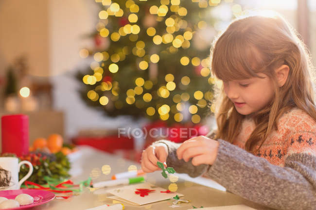 Ragazza che fa decorazioni natalizie a tavola — Foto stock