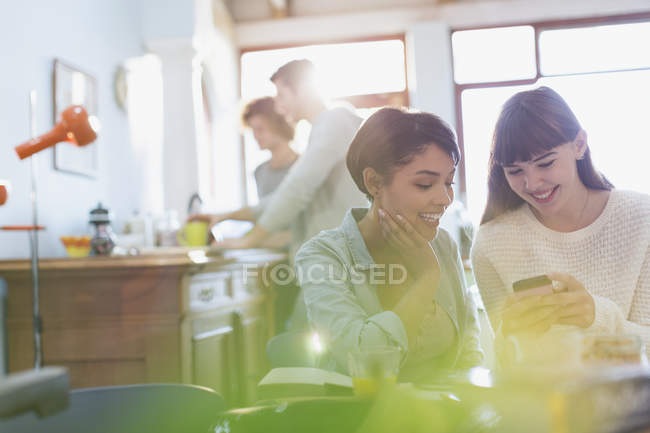 Young women texting with cell phone in apartment — Stock Photo