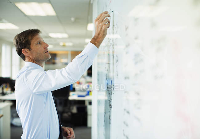 Empresário escrevendo em quadro branco no escritório — Fotografia de Stock