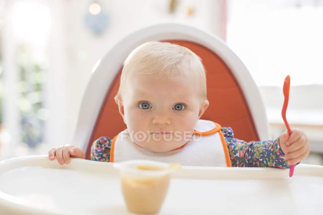 Baby girl eating in high chair — Stock Photo