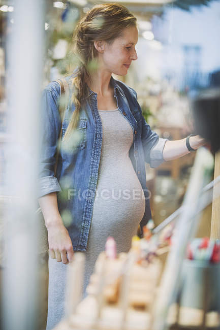 Mujer embarazada de compras en la tienda - foto de stock