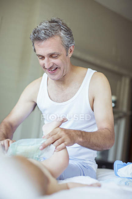 Отец меняет подгузник ребенку — стоковое фото
