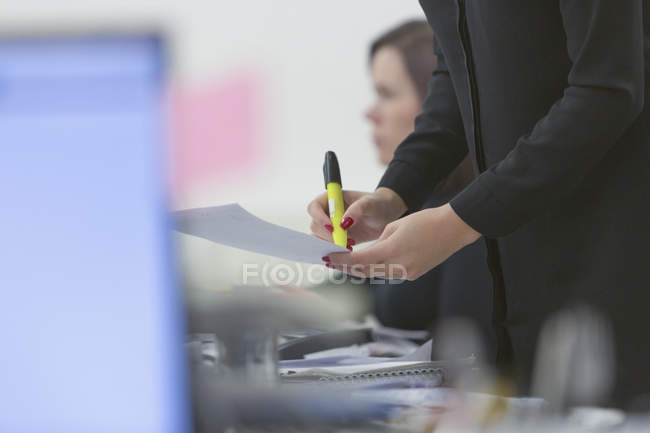 Businesswoman highlighting paperwork in office — Stock Photo