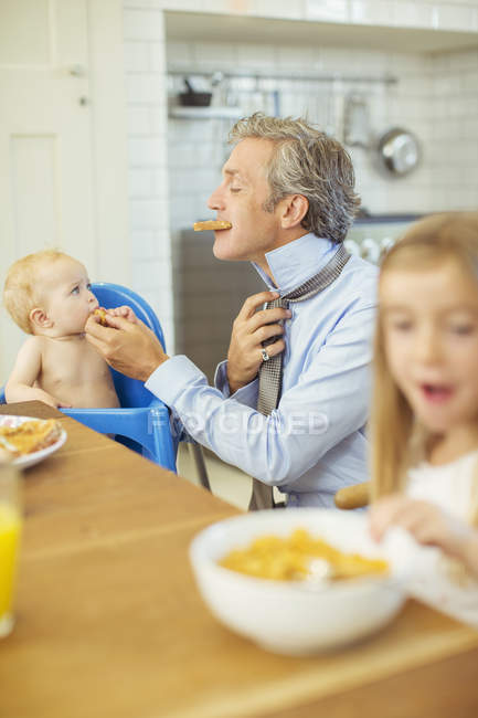 Pai e crianças tomando café da manhã na cozinha — Fotografia de Stock