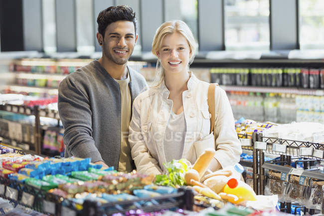 Retrato sonriente pareja joven compras en el mercado - foto de stock