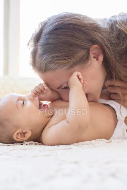 Madre soplando frambuesas en el estómago del bebé - foto de stock