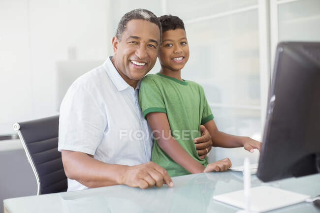 Ritratto di sorridere nonno e nipote al computer — Foto stock