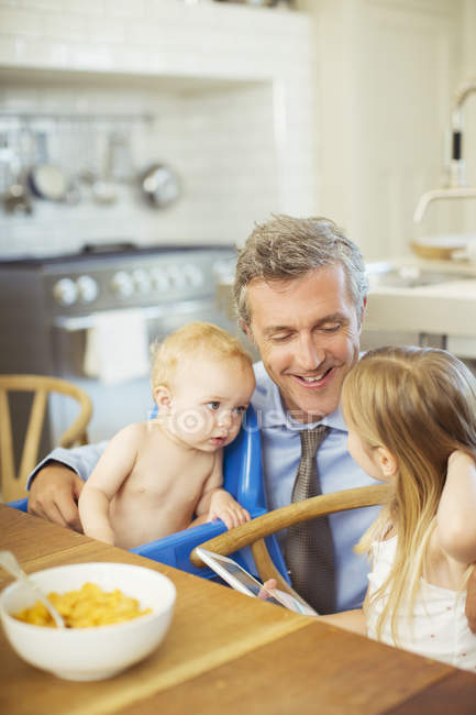 Padre hablando con los niños en el desayuno - foto de stock