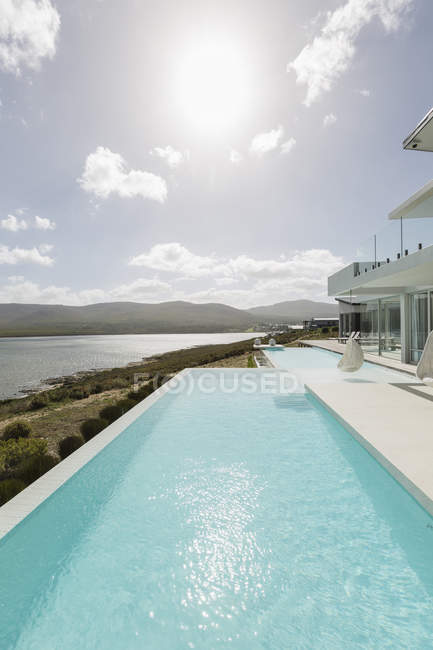 Soleado tranquilo hogar escaparate exterior piscina infinita con vista al mar - foto de stock