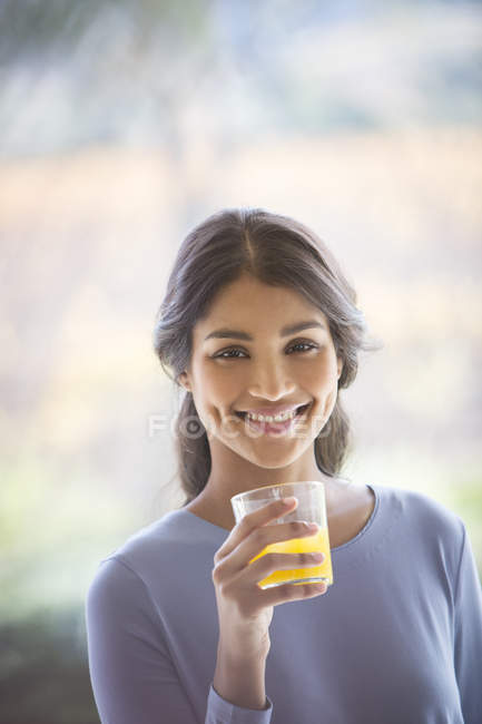 Portrait smiling woman drinking orange juice — Stock Photo