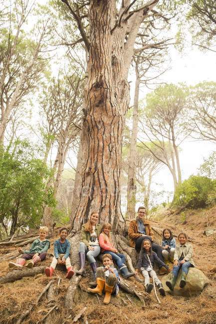 Students and teachers sitting on tree in forest — Stock Photo