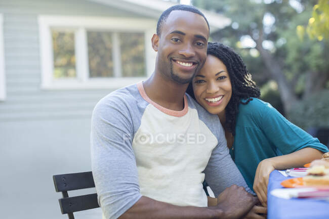 Retrato de la feliz pareja cogidos de la mano en la mesa de patio - foto de stock