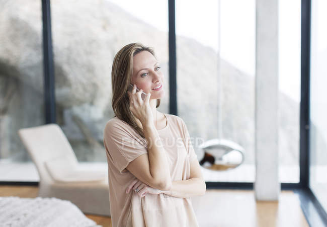 Жінка розмовляє на мобільному телефоні в сучасній вітальні — стокове фото