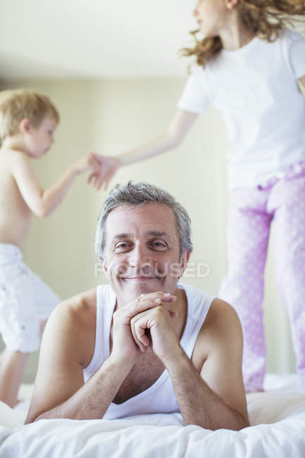 Crianças pulando na cama ao redor do pai — Fotografia de Stock