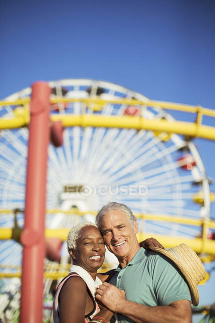 Retrato de feliz pareja de ancianos abrazándose en el parque de atracciones - foto de stock