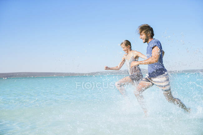 Coppia che corre in acqua sulla spiaggia — Foto stock