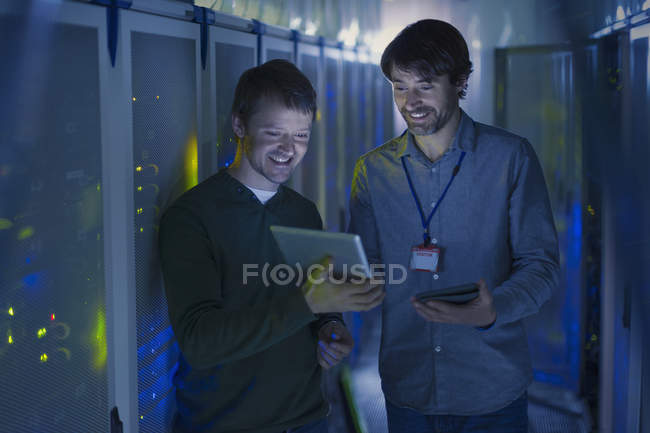 Techniciens de salle de serveurs utilisant une tablette numérique — Photo de stock