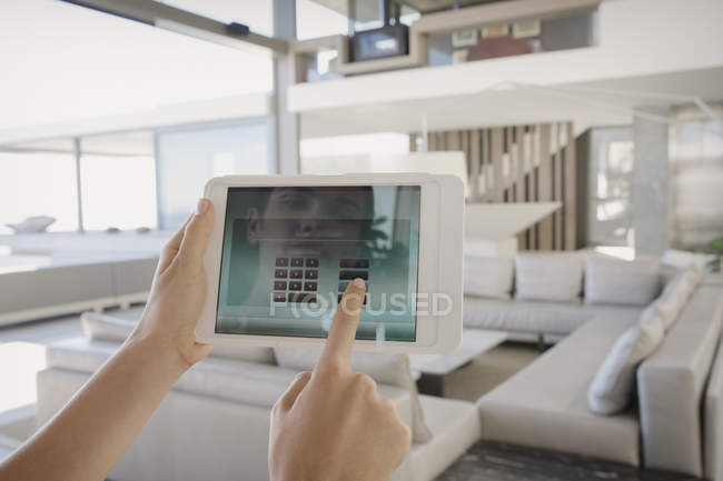 Personal perspective woman with digital tablet managing digital security system in modern, luxury home showcase interior living room — Stock Photo