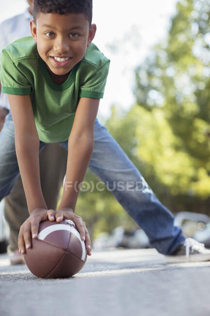Portrait of smiling boy preparing to snap football — Stock Photo