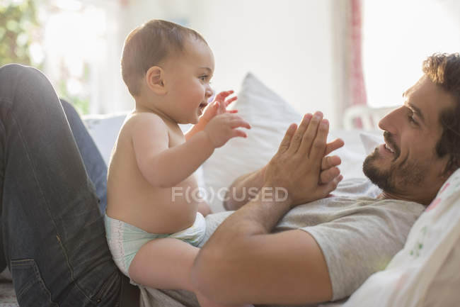Отец играет с маленьким мальчиком в постели — стоковое фото