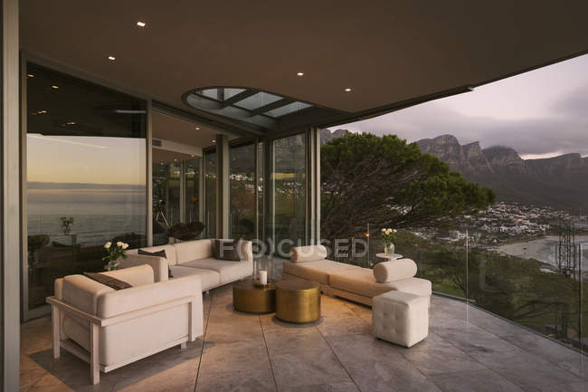Riflessione della vista sull'oceano crepuscolo sul moderno patio vetrina casa di lusso con vista sulle montagne — Foto stock