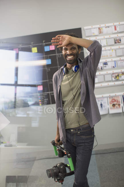 Portrait laughing creative cameraman holding camera — Stock Photo