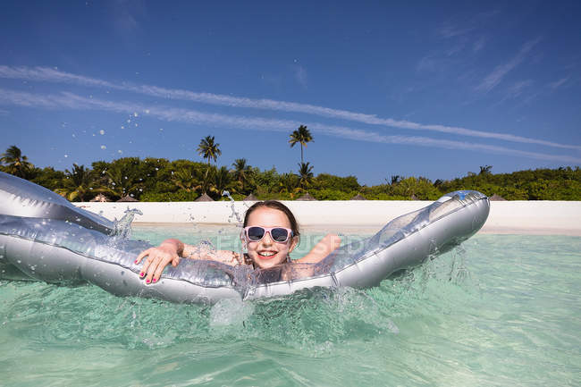 Portrait smiling girl playing with inflatable raft in sunny tropical ocean — Stock Photo