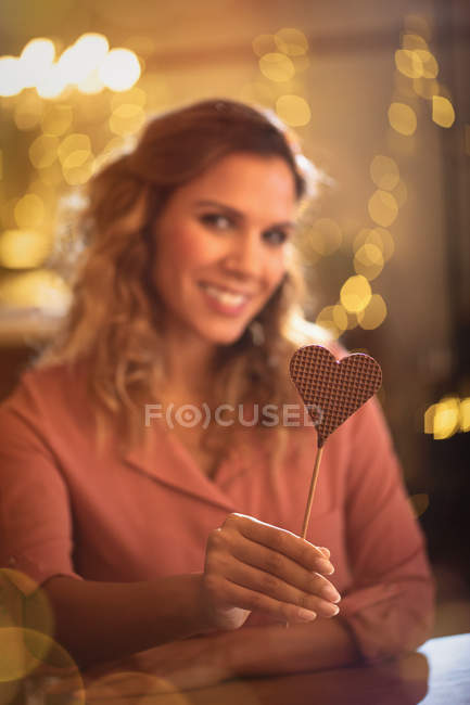 Portrait femme souriante tenant sucette en forme de coeur — Photo de stock