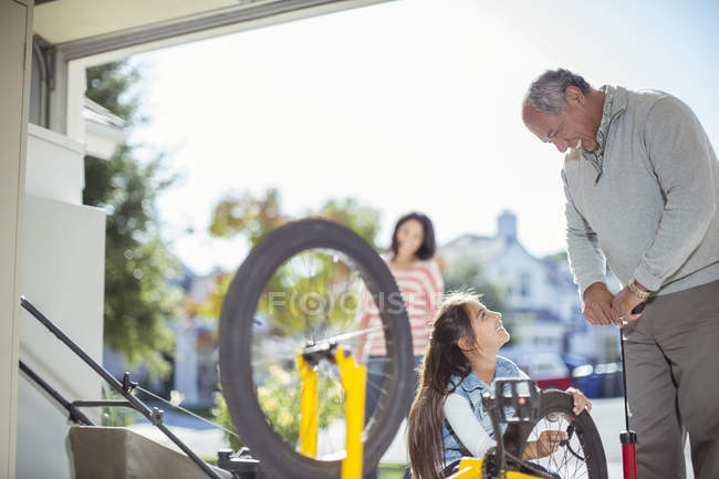 Grandfather and granddaughter inflating bicycle tire in garage — Stock Photo